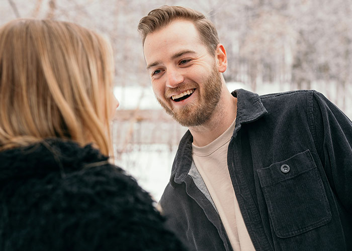 Man laughing with a woman outdoors, illustrating touchy behavior concerns.