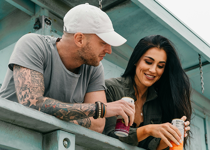 Man and woman smiling on a balcony, holding drinks; related to touchy behavior and gaslighting.