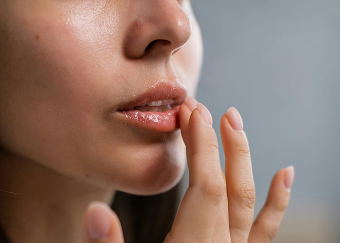Close-up of a person touching their lips, illustrating natural healing. Close-up of a person touching their lips, illustrating natural healing.
