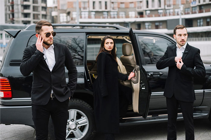 Three people in suits, standing by a black SUV, representing Hollywood secrets.