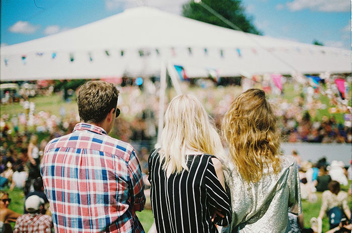 People at an outdoor festival sharing Hollywood secrets, wearing casual clothing with a large tent in the background.