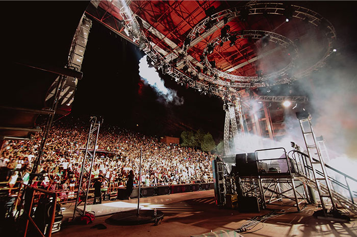 A packed concert venue with a large crowd under dramatic stage lighting, capturing Hollywood secrets atmosphere.