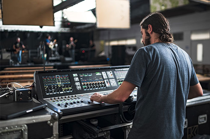 Sound engineer adjusting audio control board on a Hollywood set.