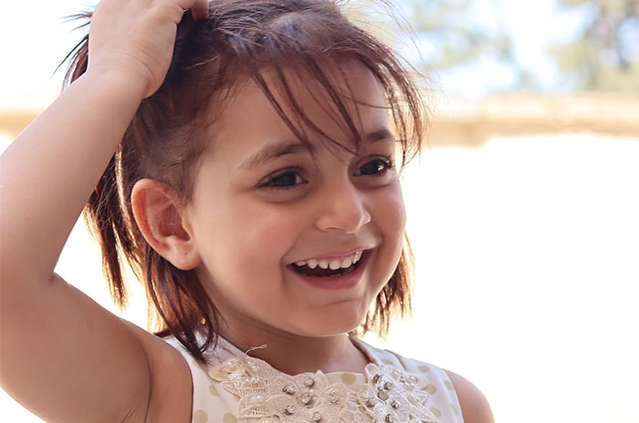 Smiling child outdoors, revealing joy and innocence, related to Hollywood secrets.