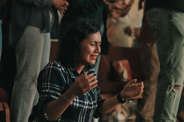 Person in plaid shirt with expressive pose during a group event, related to sharing Hollywood secrets.
