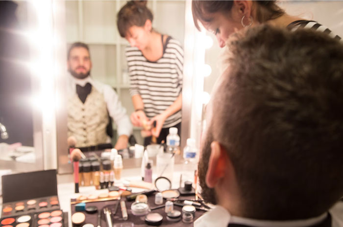 Makeup artists prepare actors backstage, sharing Hollywood secrets.