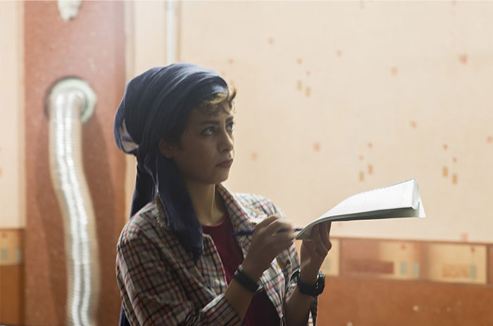 Person holding a notebook, reflecting on Hollywood secrets in a casual indoor setting.