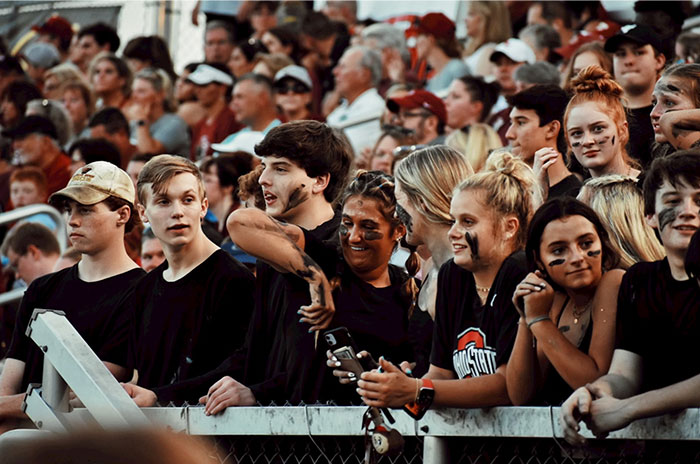 Crowd of people at an event, some with face paint, sharing lively expressions, capturing Hollywood secrets.