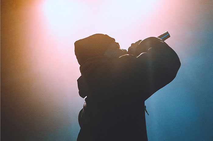 Silhouette of a person holding a microphone on stage, sharing Hollywood secrets.