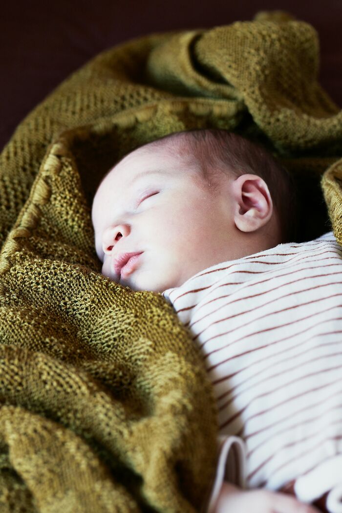 Sleeping baby wrapped in a green blanket, highlighting an incredibly lucky survival story.
