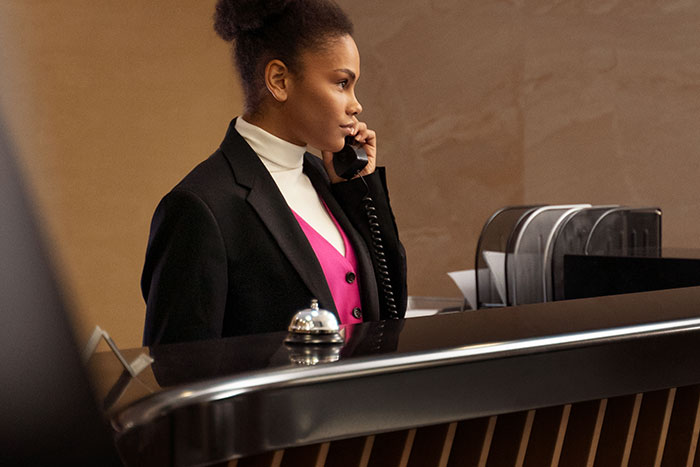 Receptionist in a professional outfit at a front desk, representing jobs with little work.