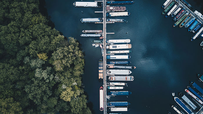 Aerial view of boats docked at a marina surrounded by green trees, illustrating relaxing environments linked to easy jobs.