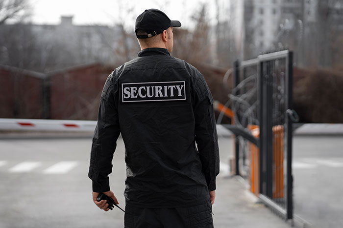 Security guard in uniform standing by an open gate, exemplifying jobs with minimal work effort.