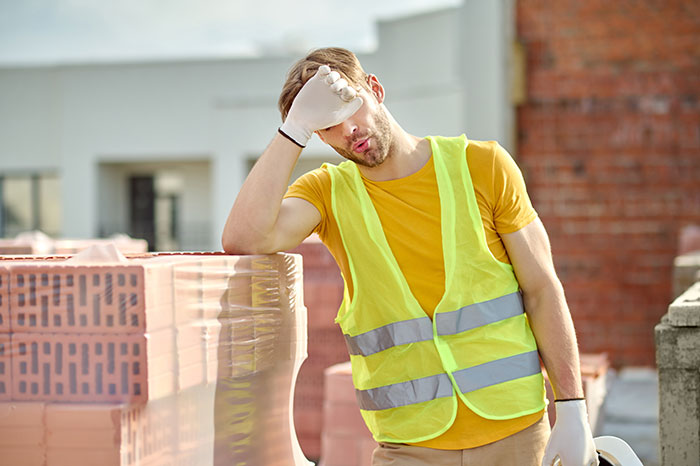 Worker in a safety vest resting on a construction site, embodying jobs with minimal effort required.