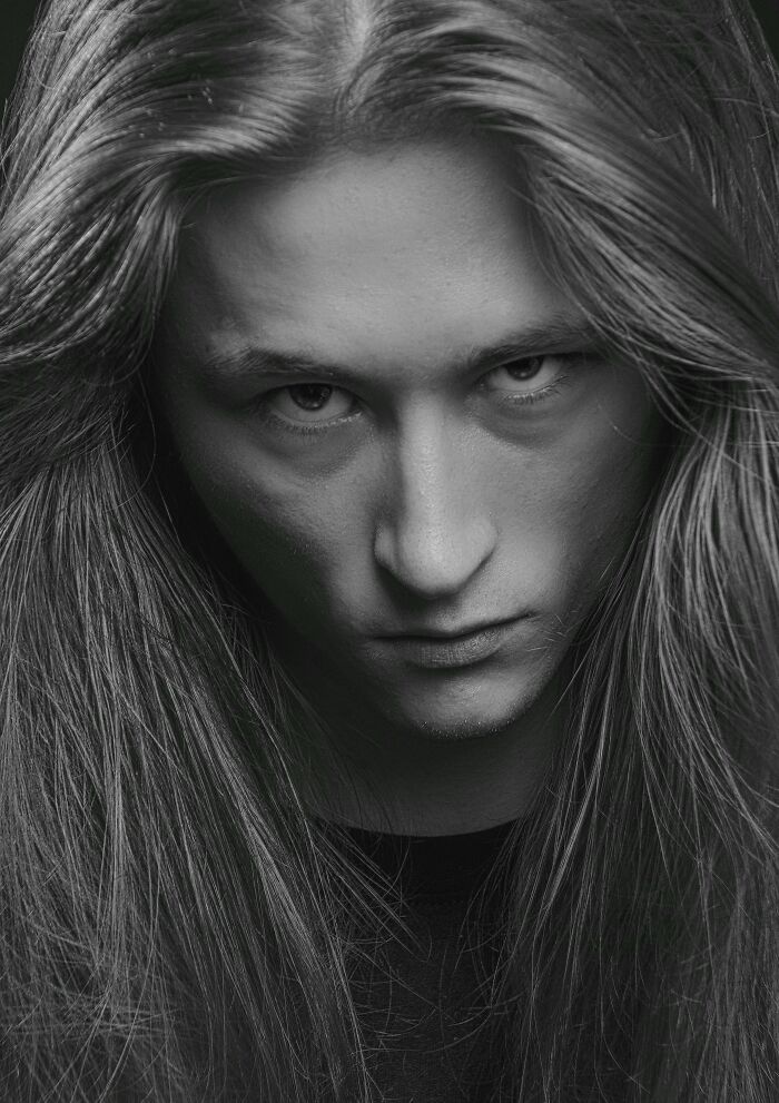 Black and white portrait of a person with long hair looking intensely at the camera, capturing a moment of cringe.