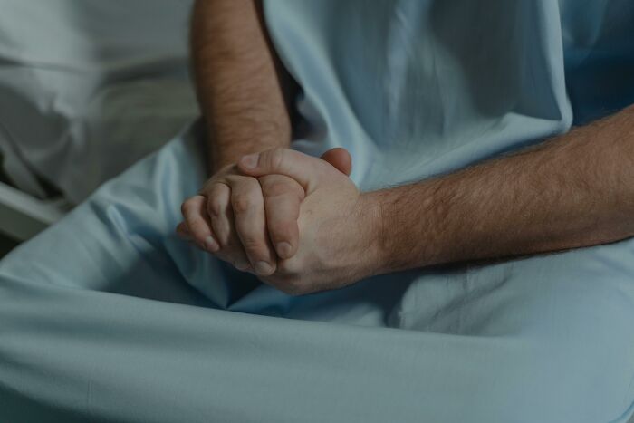 Hands clasped on a hospital gown, depicting a moment of personal cringe.