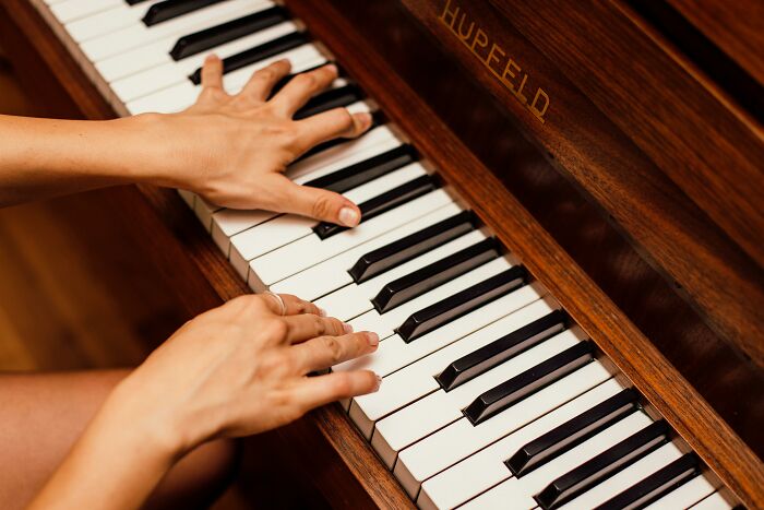 Hands playing piano keys, capturing a cringe-worthy moment with their unusual positioning.