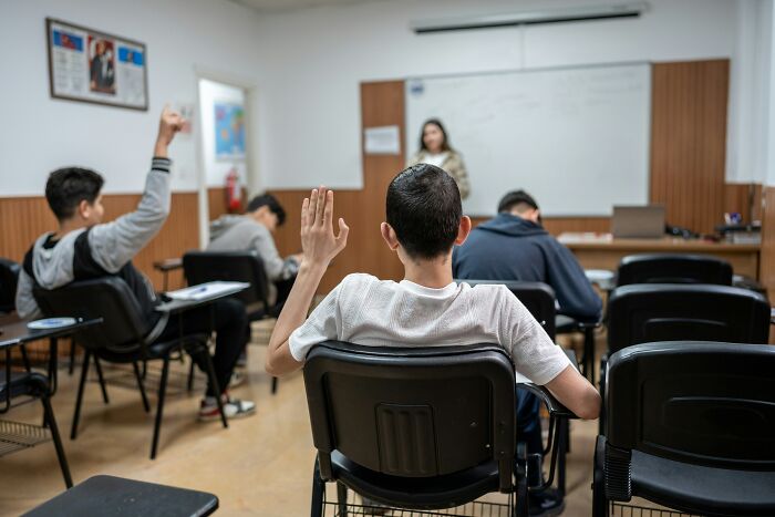 Students raising hands in a classroom setting, illustrating heights of cringe moments during a school lesson.