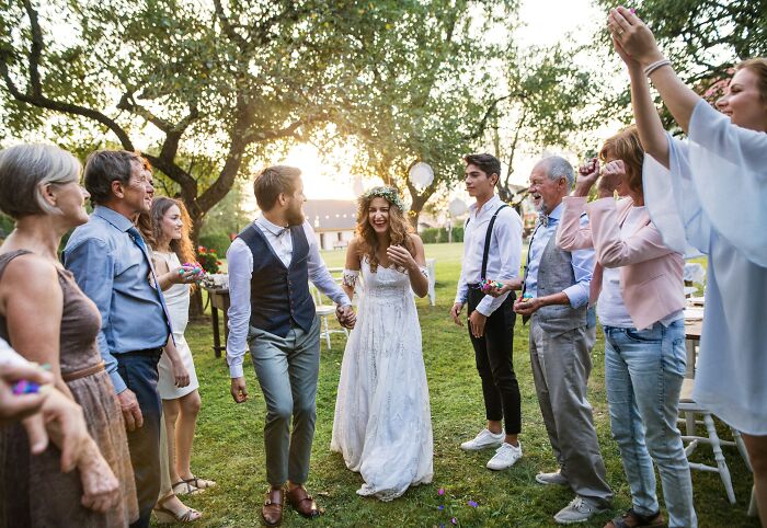 Bride and groom celebrating outdoors with a group, capturing moments of friendship and joy.