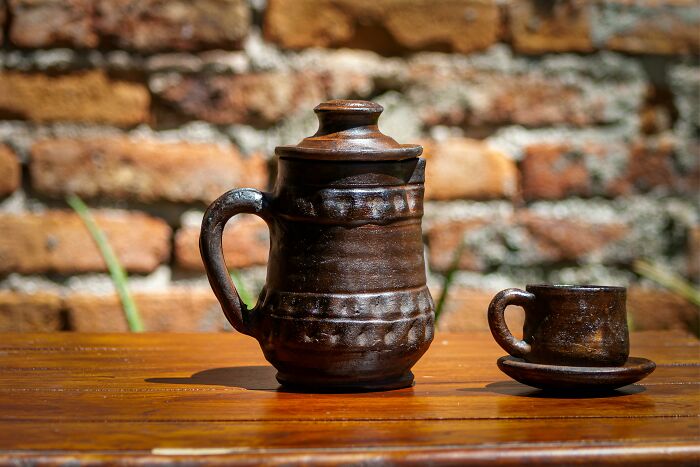 Clay teapot and cup on wooden table, showcasing frugal home hacks for a royal touch.