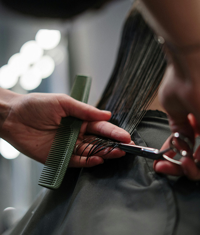 Hairdresser creating inclusive cuts, using scissors and a comb.