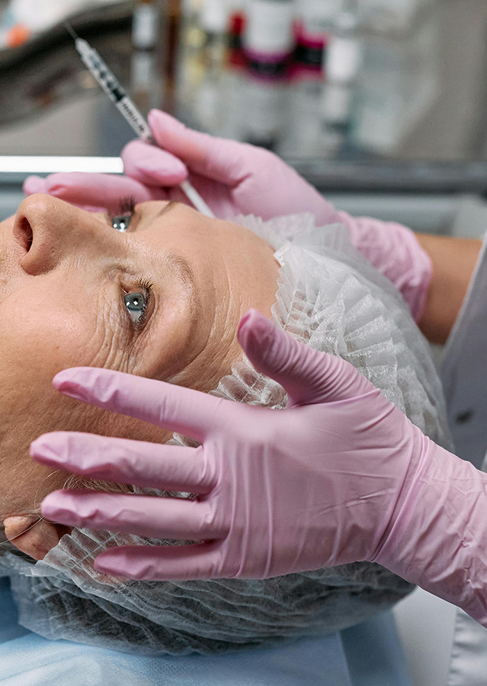 Person receiving injection, pink gloves, cosmetic procedure, beauty trend concerns. Person receiving injection, pink gloves, cosmetic procedure, beauty trend concerns.