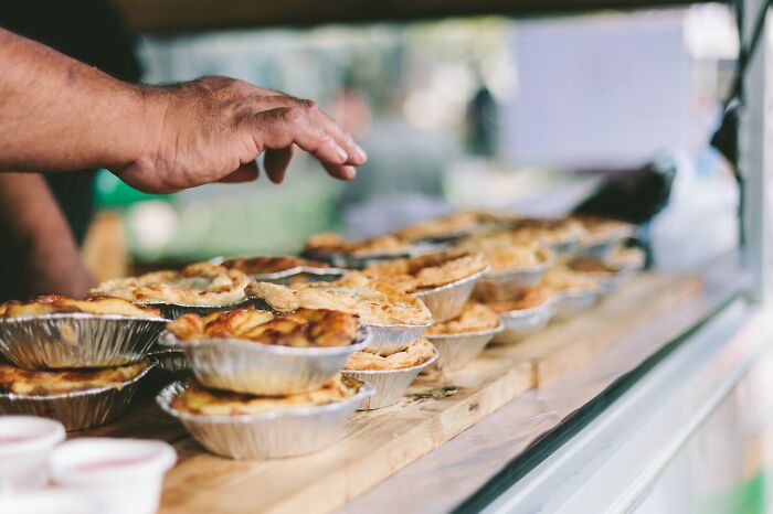 Hand reaching for pies at a potluck, capturing the festive spirit before the work Christmas party festivities.