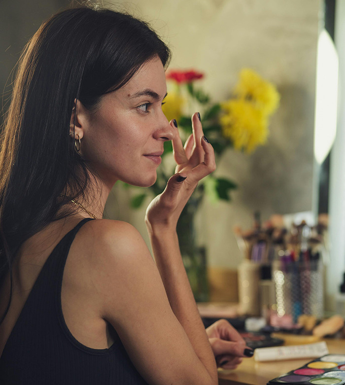 Woman applying makeup at a vanity, highlighting the "Throning" dating trend concept.