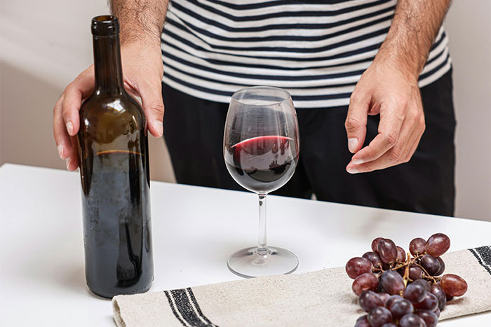 Person with wine bottle and glass, showcasing the WomenInMaleFields trend in a culinary setting.