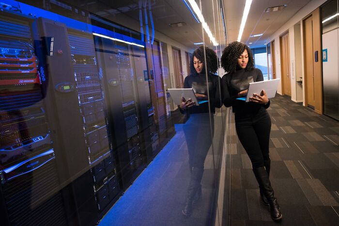 Woman with laptop in a server room, reflecting on secrets about jobs unknown to common people.