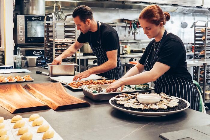 Chefs preparing dishes in a busy kitchen, showcasing how fun jobs can be less glamorous than imagined.