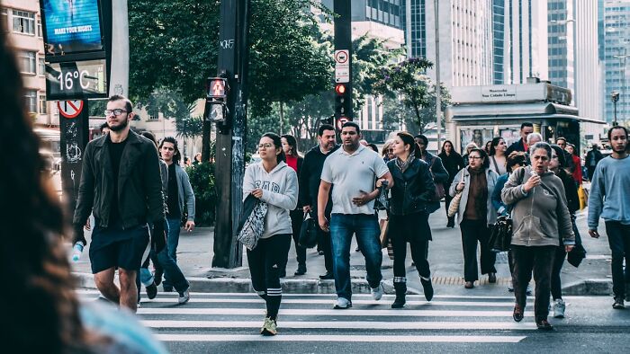 People crossing a city street, showcasing urban life and uniqueness in everyday moments.