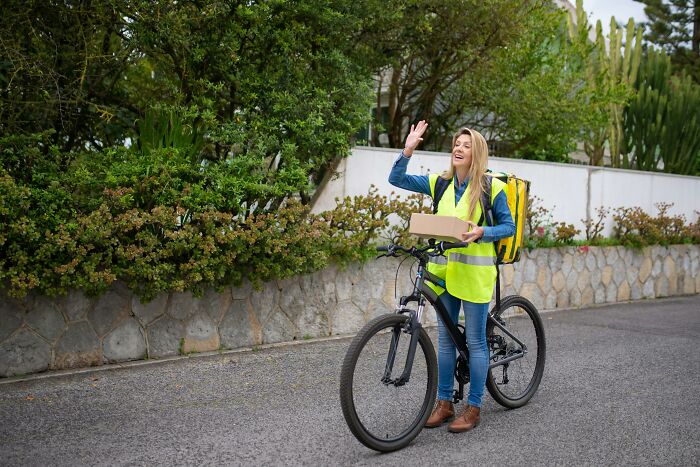 Bicycle courier in high-vis vest delivering a package, reflecting the evolution of heroic occupations over the years.