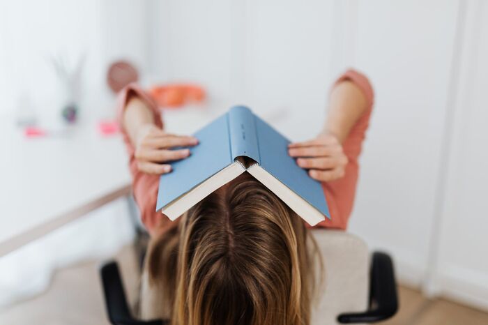 Person with a book on their head, appearing frustrated, depicting really messed up moments in a study session.
