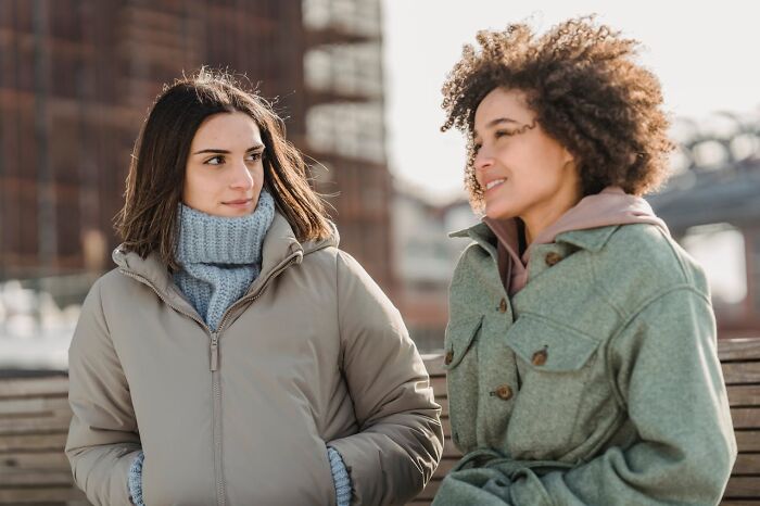 Two people in winter coats having a friendly conversation outdoors, illustrating traits of a truly good person.