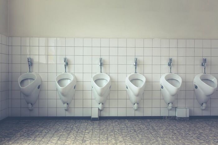 Row of white urinals in a tiled restroom, capturing an unusual work Christmas party setting.