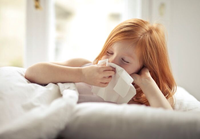 Child in bed holding tissue, relates to health myths debunked by medical professionals.