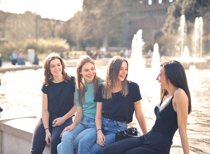 Four friends laughing together near a fountain, illustrating traits of truly good people.