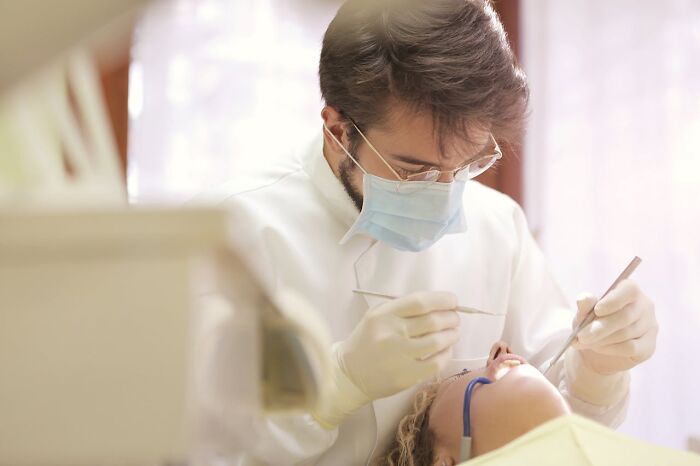 Dentist wearing a mask examining a patient's teeth, illustrating unusual facts about dental practices.