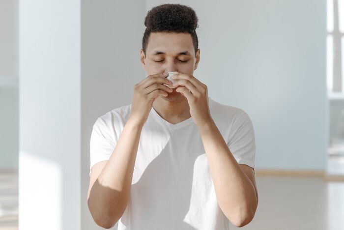 Person in a white shirt using a tissue, related to health myths and medical professionals' insights.