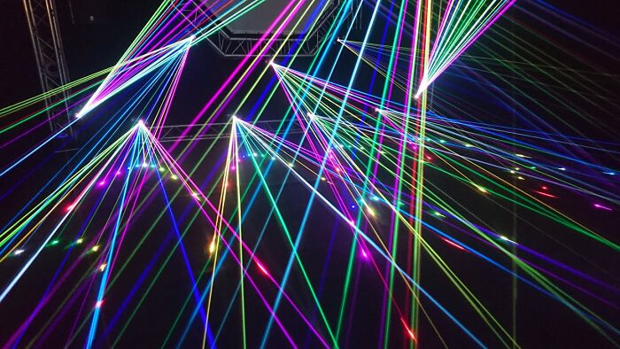 Colorful laser beams intersecting in a dark setting, showcasing an unusual light display.