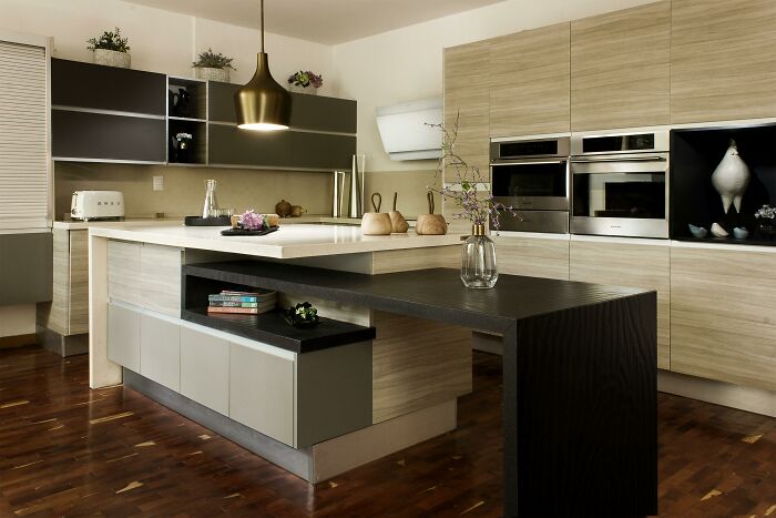 Modern kitchen with wooden flooring, featuring sleek cabinets, appliances, and elegant decor.