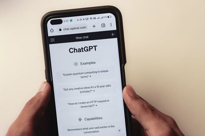 Hands holding a phone displaying ChatGPT, highlighting AI trends.