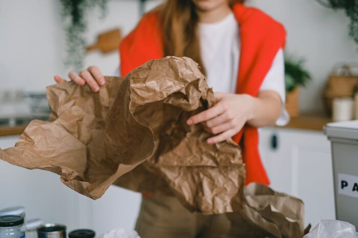 Person recycling paper in a kitchen, demonstrating a small act of kindness that reflects being a truly good person.