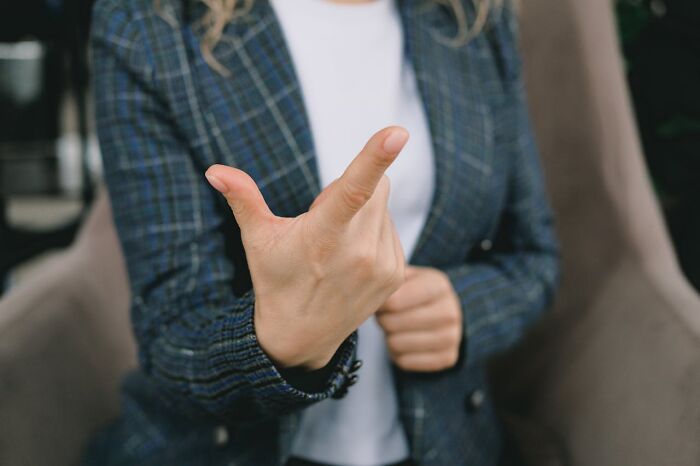 Person in plaid blazer making a finger gun gesture, expressing a moment of realization.