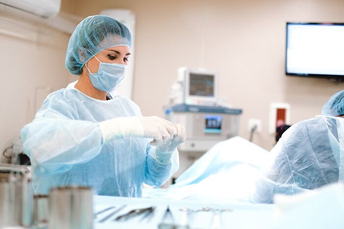 Medical professional in scrubs preparing for surgery in an operating room.