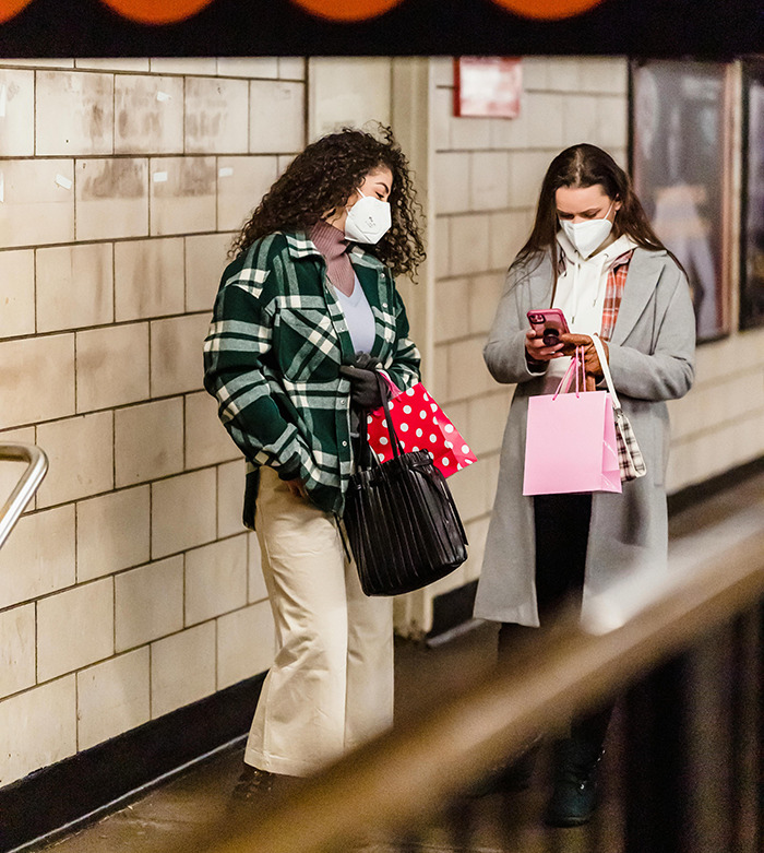 Two women using phones in a subway station, demonstrating a hack against phone snatchers. Two women using phones in a subway station, demonstrating a hack against phone snatchers.