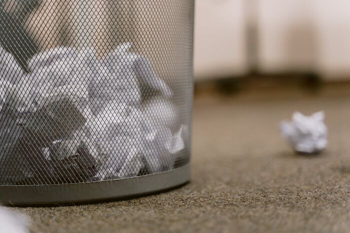 Wastebasket filled with crumpled paper, symbolizing layoffs after a potluck at a work Christmas party.