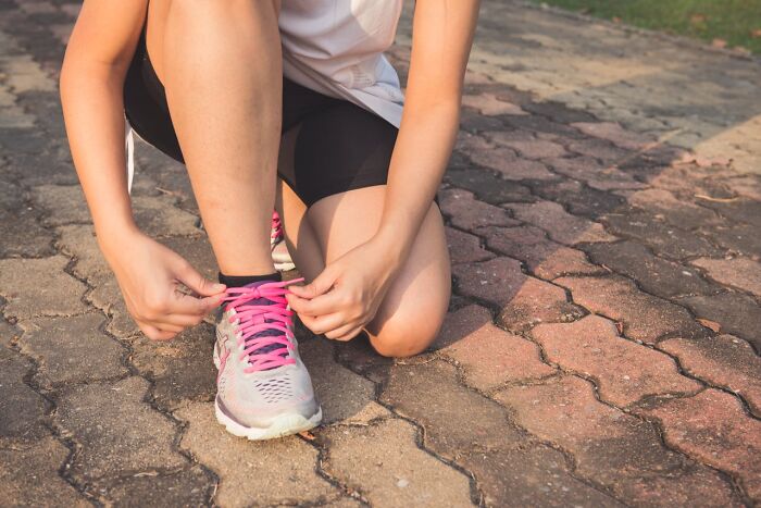Person tying pink shoelaces on running shoes, symbolizing small ways to identify a good person.
