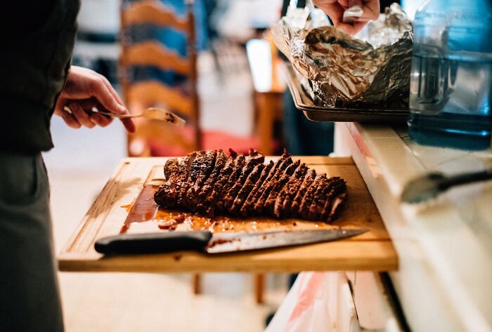 Slices of roast beef on a wooden board at a work Christmas party potluck.